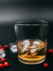 glass of whiskey with frozen berries and ice 