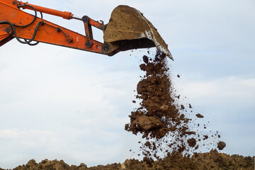 Soil spills out of the bucket of the excavator.