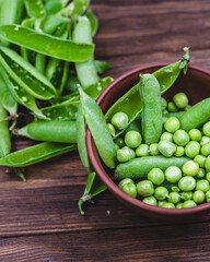 fresh green peas in a brown bowl on a wooden table