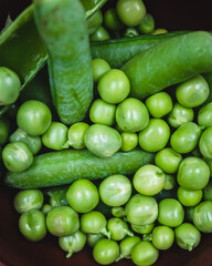 fresh green peas in a brown bowl on a wooden table
