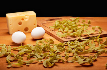 Colorful raw pasta, cheese and eggs on wooden table, healthy food concept