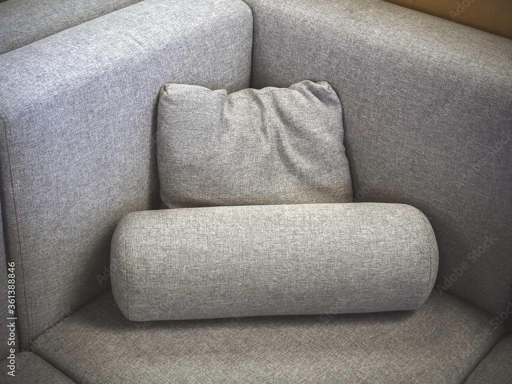 Aufkleber a closeup photo of a fragment of a soft gray fabric sofa with a square and cylindrical pillow. corne