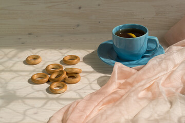 Morning tea with lemon and bagels on a wooden table. Sunlight from the window