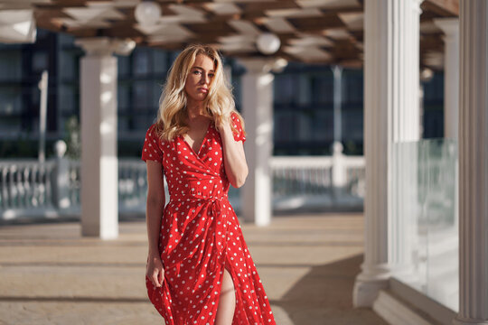 Blond young woman on red dress goes on camera