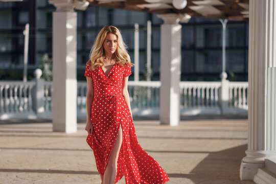 Blond young woman on red dress goes on camera