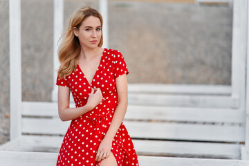 Blond young woman on red dress on beach looking to the camera