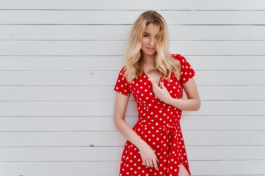 Blond young woman on red dress on beach looking to the camera