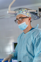 Portrait of a doctor or medical specialist. Vertical portrait. Man in scrubs. Light background with operating room. Closeup.