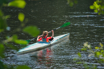 Girl climbs up the river in canoe on a sunny summer day, Miño river, galicia spain
