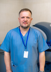 Doctor stands in hospital room . Blue scrubs. Robotic medical equipment background.