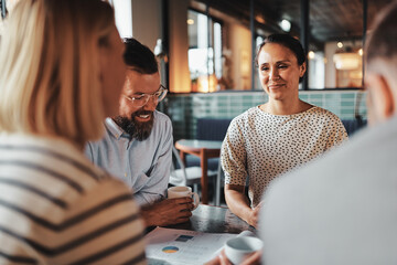 Young businesswoman having coffee with coworkers