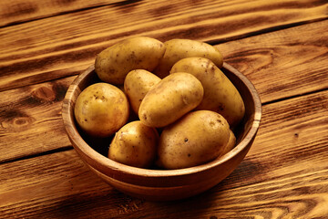 Plakat Raw new potatoes in a wooden dish on wooden background