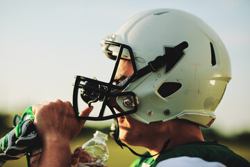 American football player drinking water during a team practice