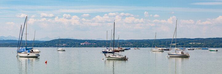 Fototapeta premium Anchoring sailboats at Lake Ammersee. Marienmuenster Diessen at the horizon.