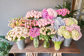 Many different colors on the stand or wooden table in the flower shop. Showcase. Background of mix of flowers. Beautiful flowers for catalog or online store. Floral shop and delivery concept. Top view