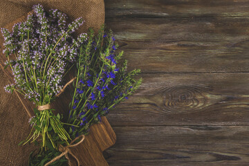 Bunches of medicinal herbs with purple and blue flowers copy space. Thyme and hyssop flowers on a wooden table flat lay.