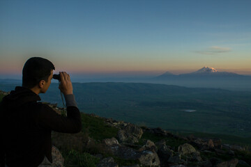 at the top of the mountain looks through a telescope at the mountain