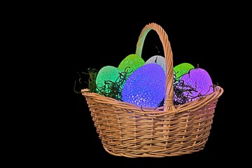 glowing Easter eggs in wicker basket with grass isolated on black