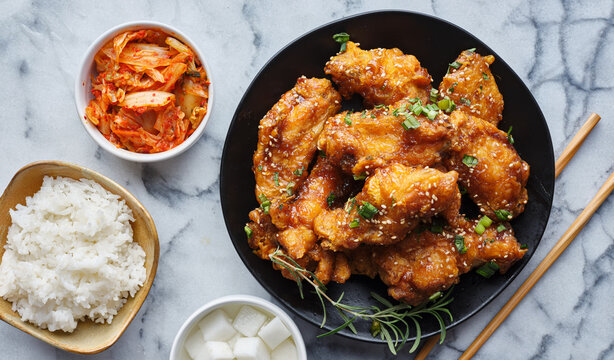 crispy fried korean chicken wings in galbi sauce with pickled radish, kimchi, and rice side dishes