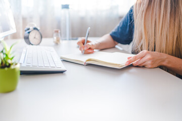 girl writes in a notebook, draws up a schedule for the week