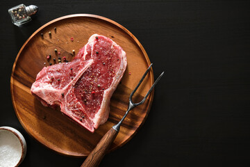 Raw T-Bone Steak with salt and pepper. Steak preparation.
