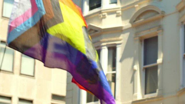 LGBTQ+ Progress Pride Flag With A Black Clenched Raised Fist In The Middle Waving And Blowing During A BLM Protest