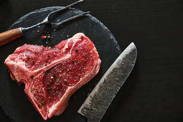 Raw T-Bone Steak with salt and pepper. Steak preparation.