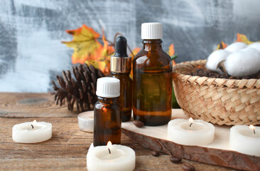 Obraz na płótnie Canvas Natural aromatherapy concept with essential oil bottle, burning candles on wooden background. Autumn spa still life composition. Cozy fall. Hygge. Copyspace.
