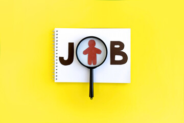 Minimalist job searching concept. Magnifier with job word, notepad on yellow background. Copyspace.