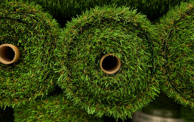green artificial grass in rolls, close up. Rolls artificial grass in store of building materials....