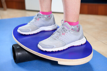Human feet in jogging shoes standing on balance board