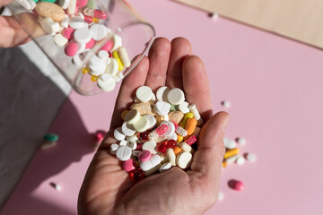 Colorful pharmaceutical medicine pills, narcotic drugs and vitamin in capsules on palm. Pouring capsules from a glass.Copy space . man holding medicine.