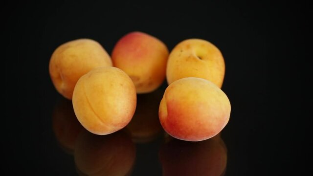 small handful of ripe apricots on black background
