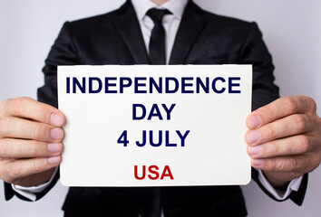 Independence Day 4th of July, an inscription on a white sheet of paper in the hands of a young man in a business suit. USA.