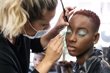 Makeup artist with mask making up a black girl