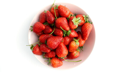 Natural fresh strawberries in a pink plate isolated on a white background, juicy berries, vegetarianism and healthy eating close-up