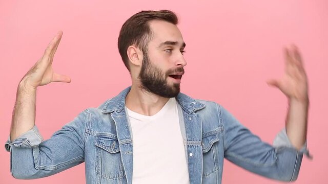 Young guy 20s years old in denim jacket white t-shirt showing blah blah gesture ja jaja hands I do not care it's all the same to me isolated on pastel pink background studio. People lifestyle concept