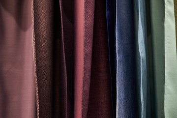 multi-colored curtains in the store. texture of multi-colored fabrics, closeup. samples of...