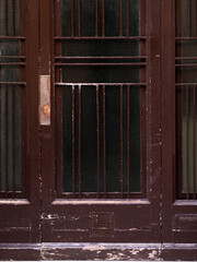 Close up outdoor view of an old and ancient wooden brown door with glass windows.Abstract architectural picture