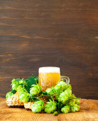 Mug of beer and fresh hops on wooden background. International Beer Day. Close-up