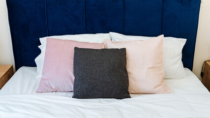 on the bed are pillows pink white and gray, made bed, bedroom interior