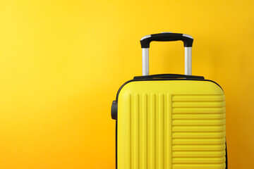 Color travel bag on yellow background, space for text