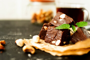Fondant on craft crumpled paper with nuts and chocolate cubes decorated with green mint leaves. In...