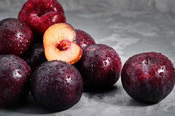 Ripe blue plums lie on a concrete stone background. Natural fruit background with place for text. Copy space. Autumn harvest background.
