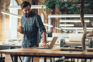 Joyful employee switching his laptop on and smiling