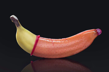 fresh banana with red condom on a black background, studio 