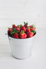 Juicy fresh strawberries in a metal bucket on a white background