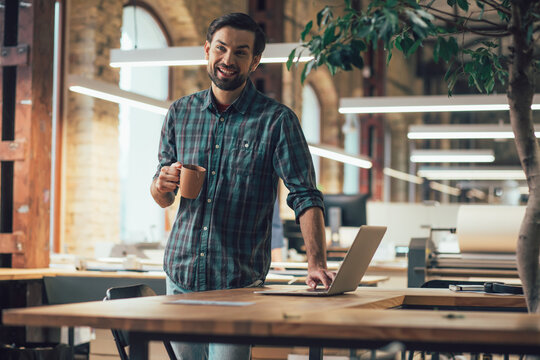 Happy employee with modern gadget and tasty coffee