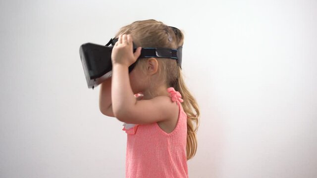 Small girl wearing Virtual reality helmet and playing virtual game at home