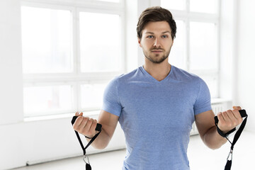 Young handsome man during workout with a resistance rubber bands in the gym.